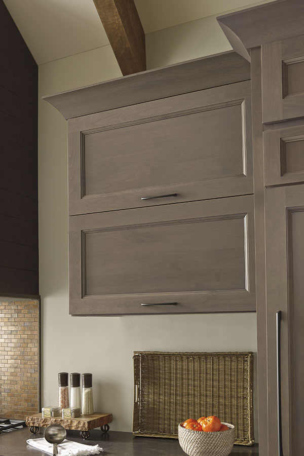 neutral colored vertical lift door hinge with kitchenware inside and bowl of fruit visible on counter
